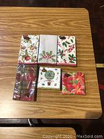 Photo of 6 packets of small Christmas napkins on a wooden table, showing various festive designs.