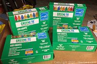 Four boxed sets of Greenlite LED holiday lights, each box labeled for indoor and outdoor use, containing 100 LED bulbs per box.