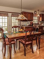 Dining table and four wooden chairs, solid wood with a rich brown finish, in a kitchen/dining room setting.
