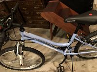 Side view of light blue Roadmaster women's mountain bike showing front suspension, frame, and tires