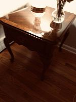 One table from a corner angle showing tabletop surface, drawer front, and leg shape