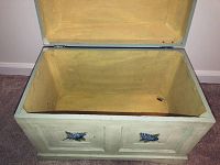 Open view of rectangular storage chest showing yellow interior lining and floral design on front sides.