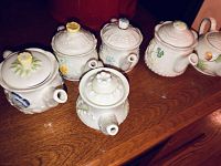 Front angle view showing all six small teapots with different floral designs and decorative lids.