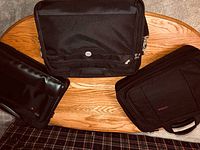 Top view of three black computer carry bags arranged on a wooden table.