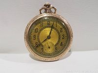 Front view of gold filled Paradox pocket watch showing yellow-gold dial, black Arabic numerals, spade hands and seconds subdial.