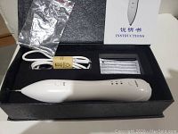 Full box contents showing white mole removal pen, power cable, sealed tips, instruction manual, and small plastic bag.