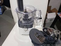 Front view of PC food processor with control dial and attachments beside it.