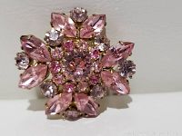 Front view of vintage pink crystal brooch showing marquise, round faceted crystals in pink and light purple shades on a gold-tone metal setting.