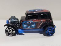 Side profile showing detailed blue face artwork on black body with red accents and chrome engine.