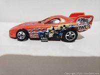 Side view of red Hot Wheels muscle car with 'Hot Wheels Power' and flame decals.