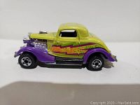 Side view of 1979 Hot Wheels die-cast car showing yellow body with purple fenders and colorful flame decal on side