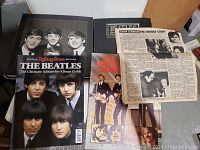 Photo showing four books about The Beatles and John Lennon with one page of newspaper about John Lennon in the foreground.