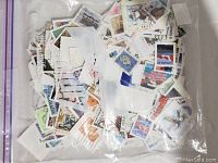 Ziploc bag filled with assorted postage stamps showing multiple designs and colors, some used with cancellation marks.