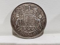 Reverse side of the 1950 Canada 50 cents coin showing Canadian coat of arms and denomination.