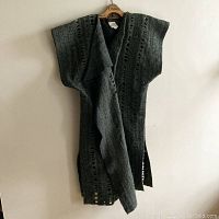 Long green alpaca vest hanging on a wooden hanger, showing full length and knit pattern