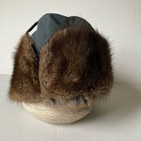 Side view showing muskrat fur trim and dark green fabric top with chin strap.