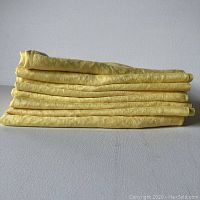 Photo of the stack of 8 hand dyed yellow linen napkins folded and laid flat, showing the texture and color.