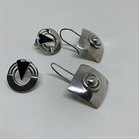Two pairs of vintage sterling silver earrings; one pair square curved drop style with bead, the other round with black triangular inlay.