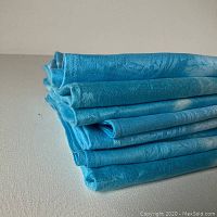 Stack of eight neatly folded blue linen damask napkins dyed with white shirbori patterns