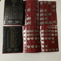 Top-down view of two red coin folders filled with Canadian nickels and dimes in clear plastic sleeves.