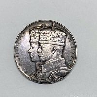 Obverse side showing left-facing crowned busts of King George V and Queen Mary with dates in Roman numerals