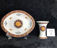 Front view of the decorative plate and vase on black background, showing their Medusa designs and ornamental borders.