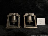 Front view of pair of antique cast iron Liberty Bell bookends showing original patination and copper highlights.