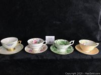Four vintage bone china teacups and saucers in a row showing different floral and decorative patterns