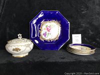 Displaying all items: four cobalt blue Aynsley floral dessert plates arranged with one vintage covered fine bone china bowl next to them on black background.