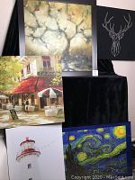 Five framed artworks arranged against a black backdrop showing the full set including city street café, tree painting, lighthouse photo, starry night inspired painting, and deer head minimalistic art.