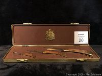Opened display case showing three folding knives with wood handles and brass bolsters.