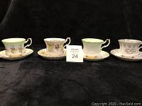 Four vintage bone china teacups and saucers with different floral and decorative designs, showing front and side views.