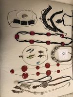 Full view of assorted costume jewelry including necklaces with red beads, black lace chokers, silver-tone bracelets, and assorted earrings.
