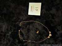 Photo showing full necklace and earrings set laid on black fabric background