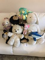 All assorted stuffed animals arranged on a couch, showing the entire lot clearly.