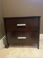 Front view of one dark brown wooden nightstand with two drawers and silver handles.