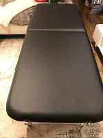 Top view of black vinyl padded massage table showing full tabletop with integrated face hole