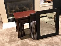 Set of three dark brown wooden nesting side tables stacked against wall