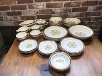 Full set of Southern Rose china displayed on wooden table showing all parts including plates, bowls, cups and saucers.