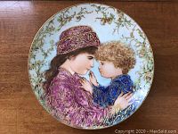Full view of the collector plate showing the mother and child illustration with vibrant colors and gold accents.