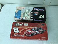 Boxes of the two NASCAR models stacked to show front box art including Budweiser No. 8 Dale Earnhardt Jr. car and Jeff Gordon No. 24 Dupont car with Looney Tunes graphics.
