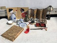 Overview image of all items described laid out on table, showing a variety of oriental decorative pieces including tea set, screens, lamp, tassels, and embroidered fabric folder.
