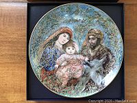 Full view of the collectible decorative plate showing the detailed artwork of a family with a donkey, surrounded by gold and floral elements.