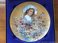 Full view of the vintage decorative plate showing girl with flowers and gold background in presentation box.