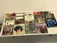 Photo showing a variety of vintage LP records arranged on a table, colorful cardboard sleeves, titles and artists can be seen, sleeves in mixed conditions