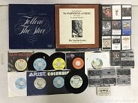 Flat lay photo of 7-inch vinyl singles, audio cassettes, and some LP sleeves showing overall contents and condition