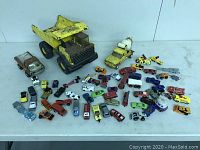 Wide view of all assortment showing dump truck, cement mixer, and many small vehicles scattered on table.