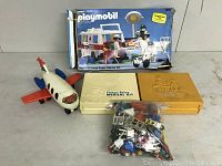 Wide shot showing all items in the lot including boxed Playmobil set, toy airplane, two Fisher-Price medical kits, and bag of loose pieces