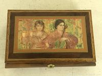 Top view of wooden keepsake box with colorful Edna Hibel artwork of two women playing instruments on lid.
