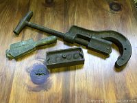 Overall view of two fishing sinker molds and one pipe cutter on a wooden surface.